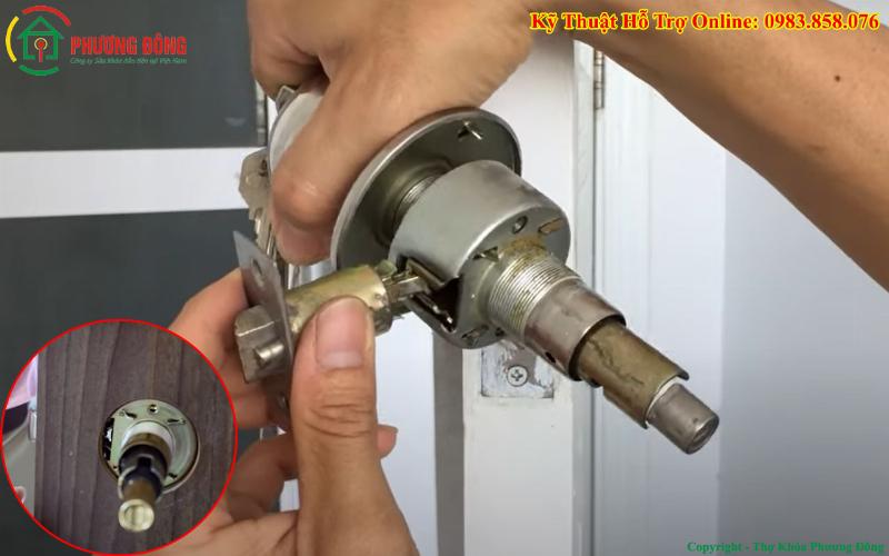 Người đàn ông đang lắp đặt ổ khóa tay nắm tròn trên cánh cửa gỗ tại nhà