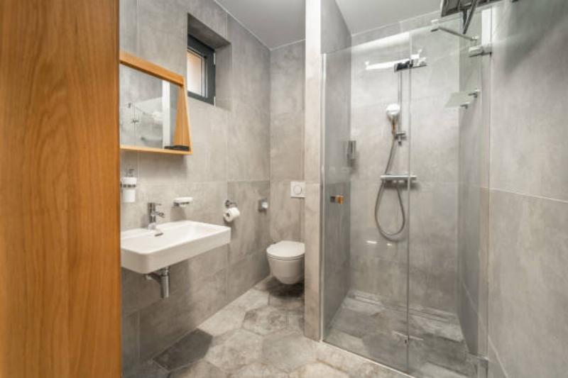 Nhà vệ sinh sang trọng với vật liệu cao cấp, gạch ốp đá vân mây, thiết bị vệ sinh mạ vàng, và gương lớn có đèn LED.