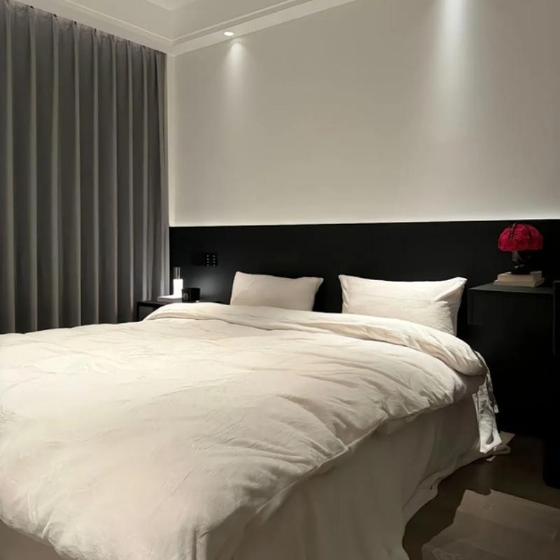 Một căn phòng khách đơn giản được bố trí hài hòa, với bộ sofa chữ L màu xám, bàn trà thấp và thảm trải sàn mềm mại, tối ưu không gian cho gia đình