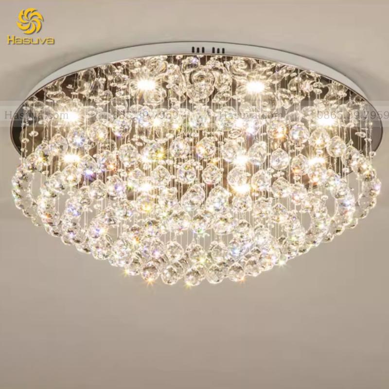 Mẫu trần thạch cao đẹp và sang trọng cho phòng khách, kết hợp với đèn chùm pha lê và hệ thống đèn âm trần tạo điểm nhấn ấn tượng