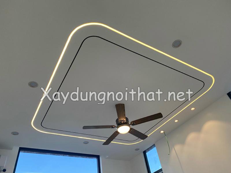 Trần thạch cao phòng khách sang trọng với thiết kế giật cấp đối xứng, tích hợp đèn LED âm trần và đèn chùm lớn.