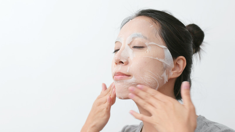 Một cô gái đang thoa kem dưỡng ẩm lên má, sau khi đã hoàn tất các bước chăm sóc da
