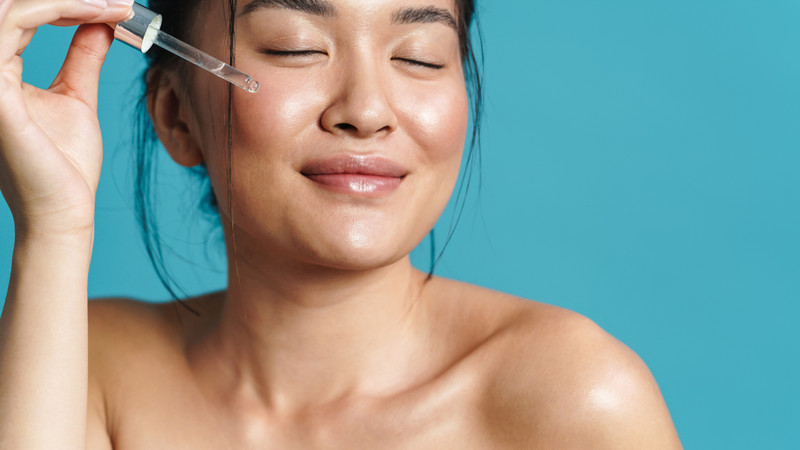 Một người phụ nữ đang thoa serum lên da mặt bằng đầu ngón tay